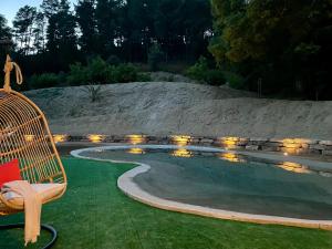 CASA RURAL EL JARDI con Piscina, Jardin y Barbacoa في Arenys de Munt: كرسي الخوص الجلوس بجوار حمام السباحة مع الأضواء