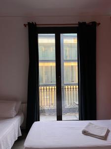 a bedroom with two beds and a glass door with a balcony at Pensión Arosa in Barcelona