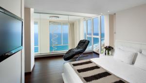a bedroom with a black chair in front of a window at Island Luxurious Suites Hotel and Spa- By Saida Hotels in Netanya