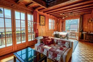 a living room with a couch and a table and windows at Le Chalet Soleil in Lathuile