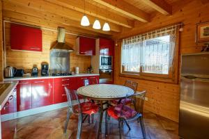 una cucina con armadi rossi, tavolo e sedie di Le Chalet Bonheur a Lathuile