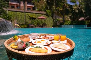 a tray of breakfast food on a table in a swimming pool at Hula Hula Resort, Ao Nang -SHA Extra Plus in Ao Nang Beach