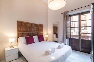 Un dormitorio con una gran cama blanca y una ventana en BnS Dauro Suites en Granada