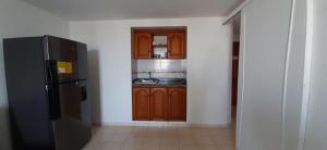 a kitchen with a black refrigerator and wooden cabinets at Apartamento en el Laguito Cartagena in Cartagena de Indias