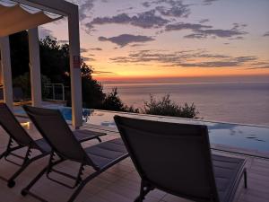 2 sillas sentadas en un balcón con vistas al océano en Bergeggi Tindari Sunrise, en Bergeggi