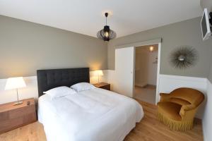 a bedroom with a large white bed and a chair at Gite Urbain Henri et Joseph in Lorient