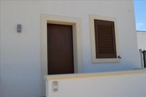 un bâtiment avec une porte marron et une fenêtre dans l'établissement Li Uluzzi, à Nardò
