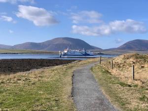 a boat docked on the water with mountains in the background at Orkney Lux Lodges - Hoy Lodge in Stromness