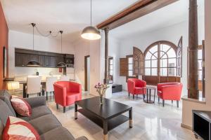 an open living room and kitchen with red chairs and a table at BnS Dauro Suites in Granada