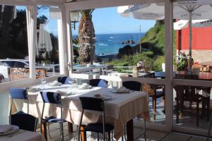 a restaurant with tables and chairs with a view of the ocean at Hotel Azpiazu in Muros de Nalón