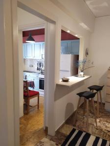 una cocina con armarios blancos, encimera y taburetes en Maria's Cozy apartment in Palaio Faliro, en Atenas