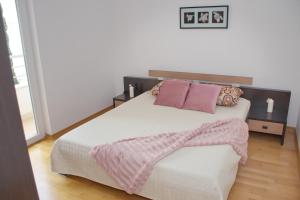 a bedroom with a large bed with pink pillows at SunShine in Novalja