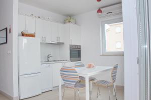 a kitchen with white cabinets and a white table and chairs at SunShine in Novalja