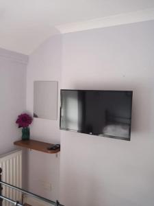 einen Flachbild-TV, der an einer weißen Wand hängt in der Unterkunft Daisys cottage. Blaenau ffestiniog. in Blaenau-Ffestiniog