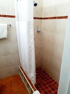 a shower with a white shower curtain in a bathroom at Parador Guánica 1929 in Guanica