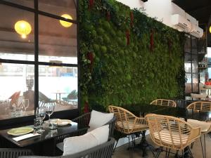 a restaurant with a green wall with tables and chairs at Hotel Suites Feria de Madrid in Madrid