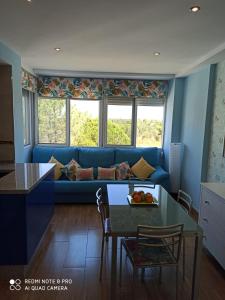 a living room with a blue couch and a table at APARTAMENTO EN ROMPIDO con piscina, chiringuito y pistas in Huelva