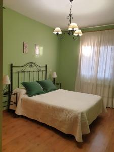 Un dormitorio con una cama con paredes verdes y una lámpara de araña. en Los Guijos, en Hoyos del Espino