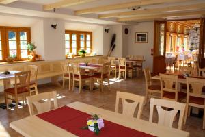 un ristorante con tavoli e sedie in legno e finestre di Hotel Aplis a Ovaro