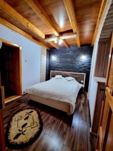 1 dormitorio con cama y pared de ladrillo en Zumzetul Raului, en Rucăr
