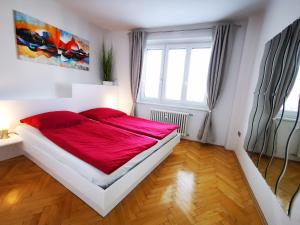 um quarto com uma cama grande e lençóis vermelhos em Charmante Zentrumswohnung mit Balkon und 80 zoll TV em Klagenfurt