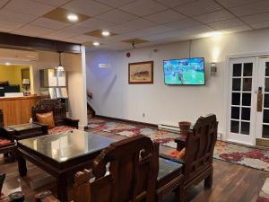 sala de estar con mesa y TV en la pared en Hotel Cowansville, en Cowansville