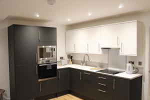 a kitchen with black cabinets and white appliances at Luxury 1 Bed Apartment In The Heart Of Rochester in Wainscot