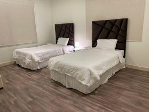 ein Hotelzimmer mit 2 Betten mit weißer Bettwäsche in der Unterkunft Sunset Alula Villa- العلا in Ar Riḩāb