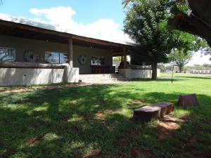 una casa con un banco en el césped en Die Olyfhuis, en Barkly West