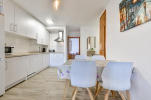 eine weiße Küche mit einem Tisch und weißen Stühlen in der Unterkunft Apartamento "Casa Auri" con Piscina, Wi-fi y Parking Gratis in Calpe