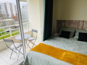 a bedroom with a bed and a balcony with a table and chairs at Spacieux studio sans vis à vis in Chelles