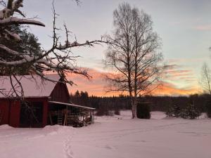 un granero en un campo cubierto de nieve con un árbol en Härlig Heden Vakantie Appartement, en Råda