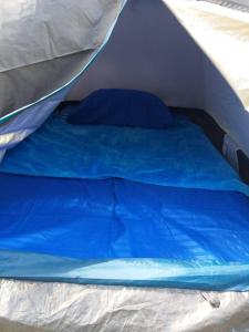 uma cama numa tenda com lençóis e almofadas azuis em La Cima Tayrona em Santa Marta