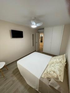 a bedroom with a large white bed and a tv at Girasol Altea Playa in Altea