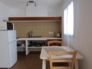 una pequeña cocina con mesa y nevera blanca en VIVIENDAS TURISTICAS CAN MARIANO BARBER - ES CALÓ - FORMENTERA, en Es Caló