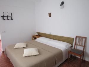 una camera con letto e sedia in legno di VIVIENDAS TURISTICAS CAN MARIANO BARBER - ES CALÓ - FORMENTERA a Es Caló de Sant Agustí