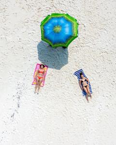 two people are laying on the beach with an umbrella at Summer Vibes Beach Front in Rasdhoo