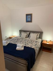 a bed in a room with two night stands and two tables at Apartmani California in Podgora