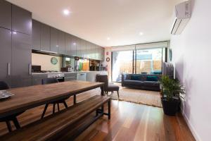 eine Küche und ein Wohnzimmer mit einem Holztisch und Stühlen in der Unterkunft Experience Port Melbourne in Melbourne