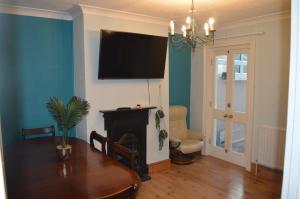 sala de estar con mesa y TV en la pared en The Crandale House Vacation Home, en Bath