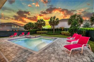 een zwembad met stoelen en een zonsondergang op de achtergrond bij Spacious 8 BDR Family Home with Arcades and Free Pool Heat in Orlando