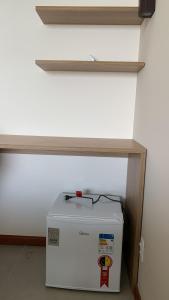 una nevera blanca sentada bajo un estante en una habitación en Nosso Recanto en Porto de Sauipe