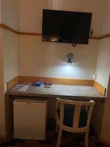 a kitchen counter with a chair and a television on the wall at Oscar Hotel in Florianópolis