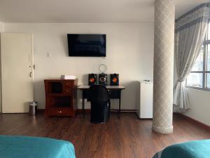 a living room with a desk with a tv and a table at Hotel Lourdes la 62 in Bogotá