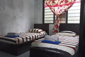 2 camas individuales en una habitación con ventana en HOME2STAY CHE MAIL 2 KUALA ROMPIN, en Kampong Perpat
