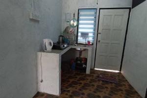 una pequeña cocina con fregadero y puerta blanca en HOME2STAY CHE MAIL 2 KUALA ROMPIN, en Kampong Perpat
