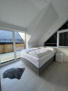 a white bedroom with a bed and large windows at Hytte på sørlandet in Kristiansand