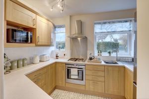 a kitchen with wooden cabinets and a stove top oven at Kist Accommodates - Stylish Headingley Apartment - Parking - 500 mps WIFI in Meanwood