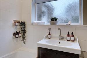 a white bathroom with a sink and a window at Kist Accommodates - Stylish Headingley Apartment - Parking - 500 mps WIFI in Meanwood