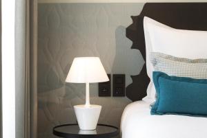 a white lamp on a table next to a bed at Hotel D - Strasbourg in Strasbourg